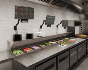 E5 wall-mounted monitor arms supporting KDS displays in a commercial kitchen food prep area