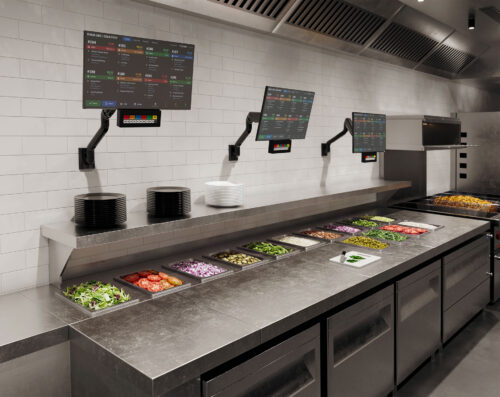 E5 wall-mounted monitor arms supporting KDS displays in a commercial kitchen food prep area